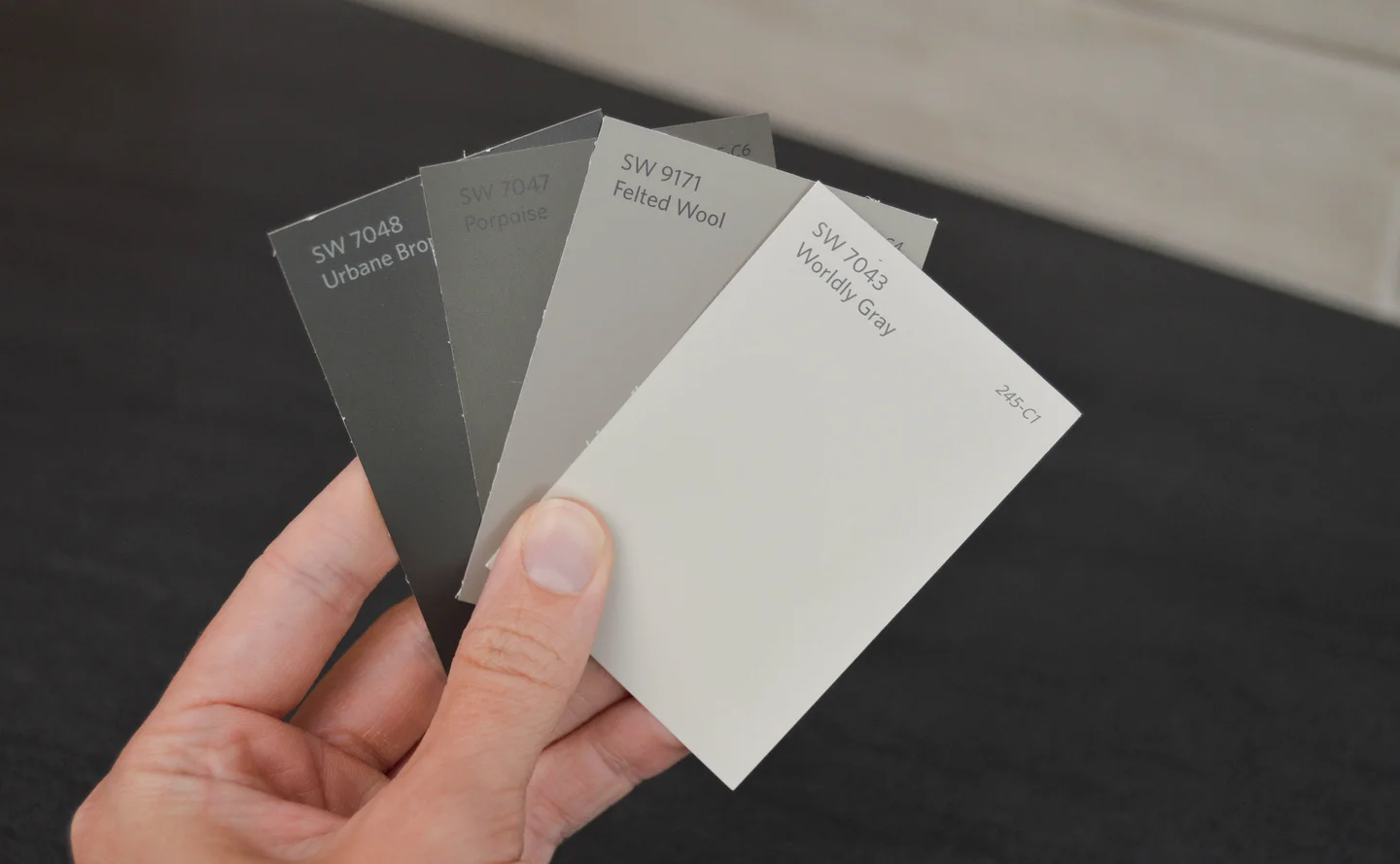 Hand holding various shades of gray paint swatches
