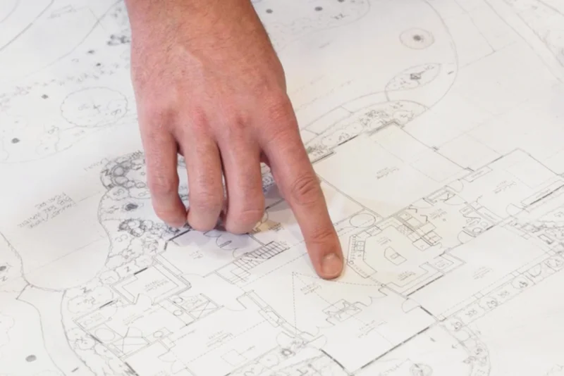 Hand pointing at details on a page of blueprint plans