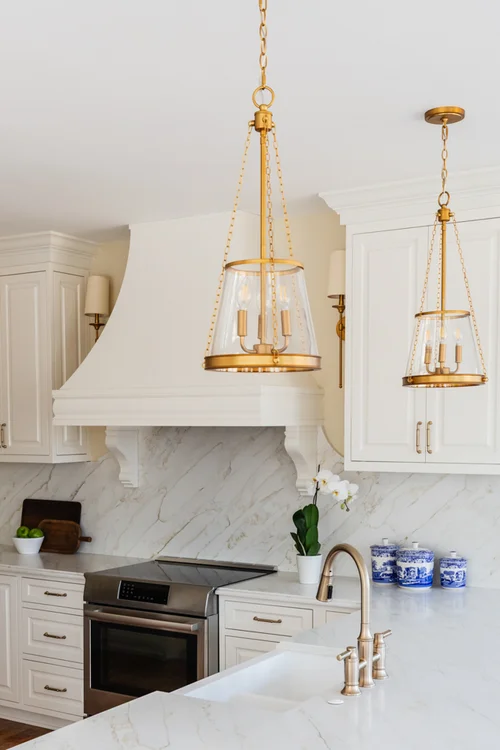 Timeless kitchen with white cabinets and brass light fixtures over the island